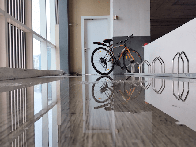 A hybrid bicycle parked on a wet floor that creating a crisp, symmetrical reflection.